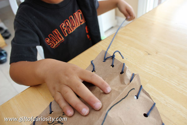 Sew your own pirate ship fine motor craft. Kids can make their own pirate ships by lacing together two sides of a boat cut from grocery store bags. #finemotor || Gift of Curiosity