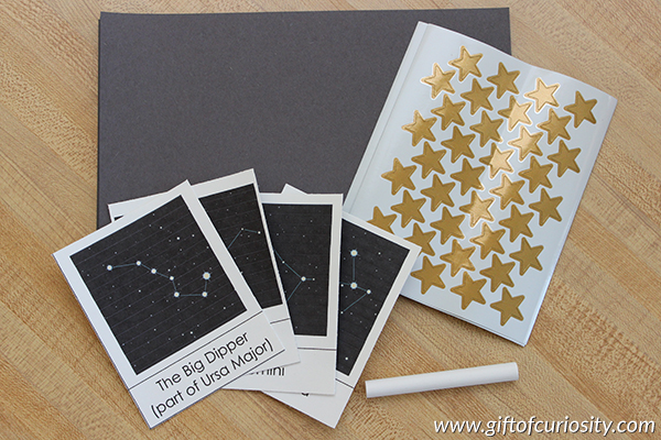 A fun constellation craft for kids using gold stars and chalk on black paper. This craft builds constellation knowledge and supports the development of fine motor skills and spatial awareness. || Gift of Curiosity