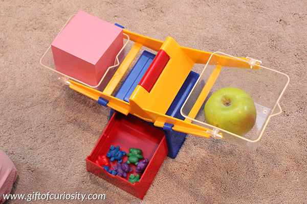 What weighs more than an apple? I love this preschool math activity that helps children learn about weight and compare quantities. This activity can easily be adapted to use other objects to fit other themes. || Gift of Curiosity
