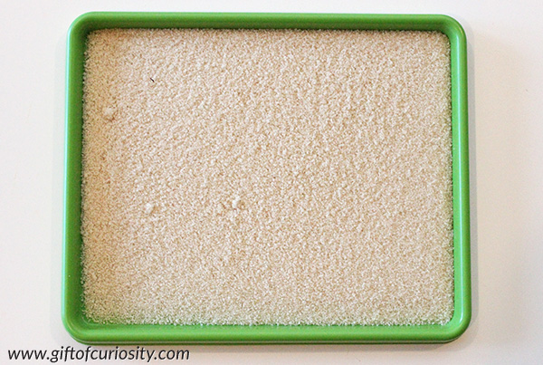 Writing letters in a salt tray is a Montessori-inspired, low-stress way for kids to practice correct letter formation. Find out why salt trays make it easy for kids to move on when they make a mistake. || Gift of Curiosity