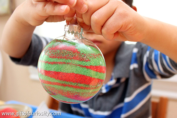 Kids can make their own sand-filled Christmas ornaments to decorate the tree this year. This is a great Christmas craft for kids who enjoy making their own ornaments. What a great idea to have something kid-made up on the tree! || Gift of Curiosity
