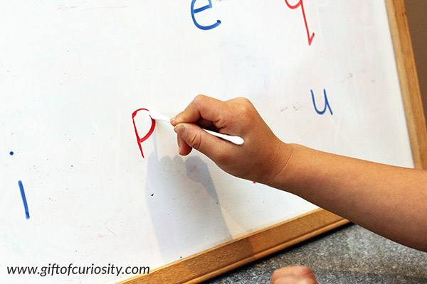 Erasing letters with a Q-tip is a simple-to-set-up activity that works on letter recognition, the proper strokes for writing letters, and fine motor skills needed for writing. I love how this activity can be adapted to help kids with any letters of the alphabet they need assistance with. || Gift of Curiosity