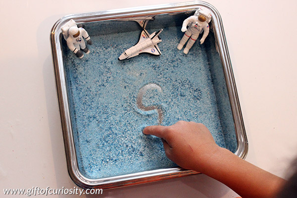Space Sensory Writing Tray using colored salt. What a fun tool for teaching space-loving kids how to write their letters! || Gift of Curiosity