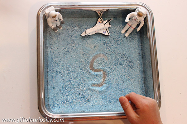 Space Sensory Writing Tray using colored salt. What a fun tool for teaching space-loving kids how to write their letters! || Gift of Curiosity